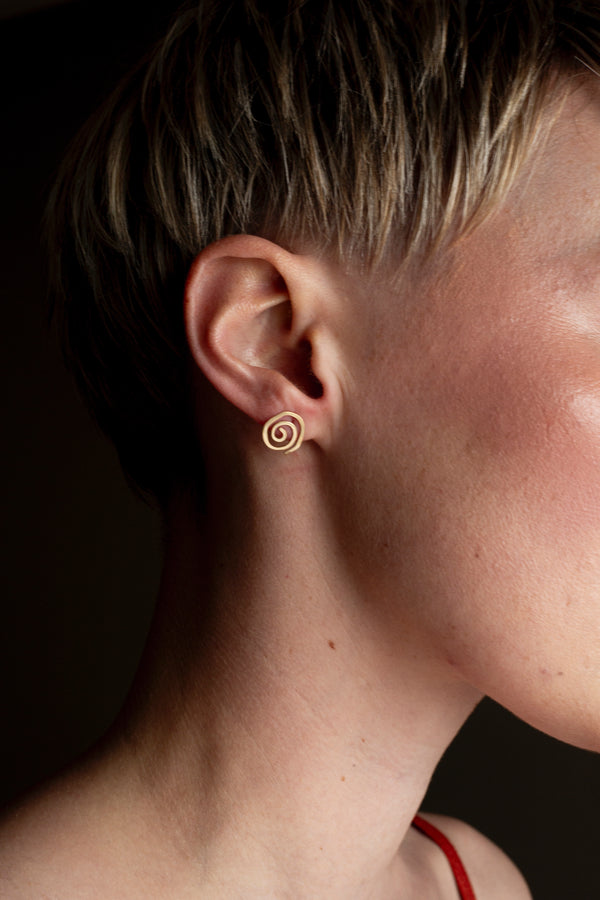 Model wearing delicate 9ct gold spiral studs, perfect for everyday wear