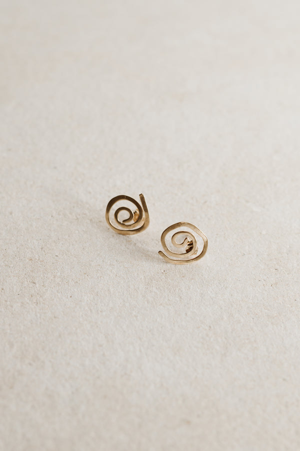 A pair of 9ct gold spiral stud earrings on a beige background.