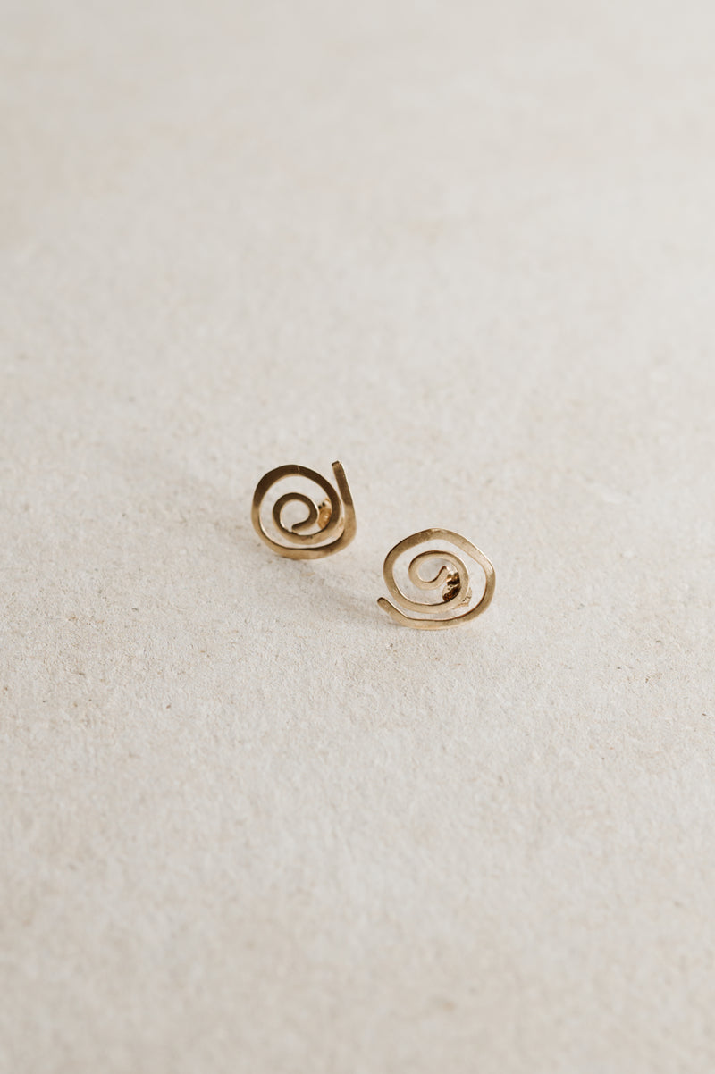 A pair of 9ct gold spiral stud earrings on a beige background.