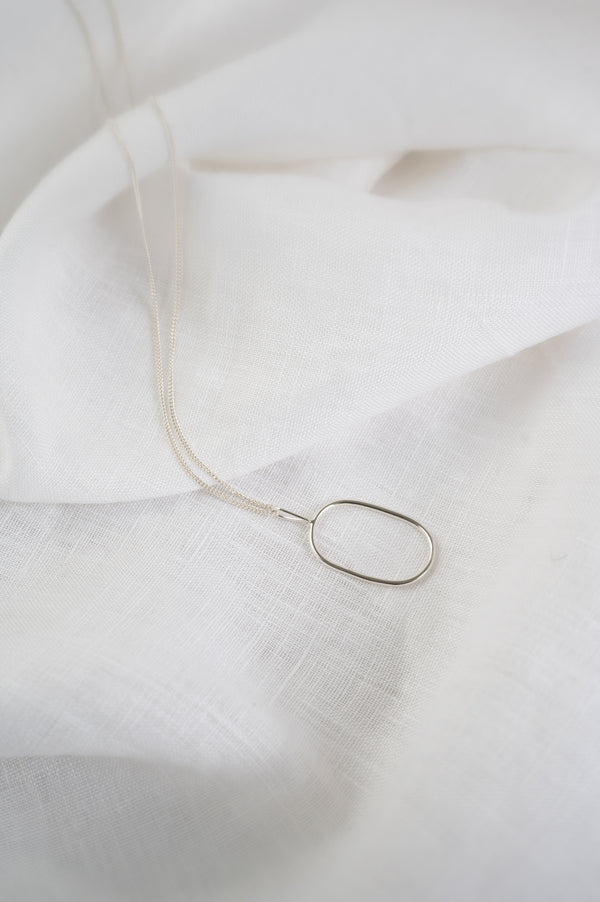 Silver necklace on a white fabric background