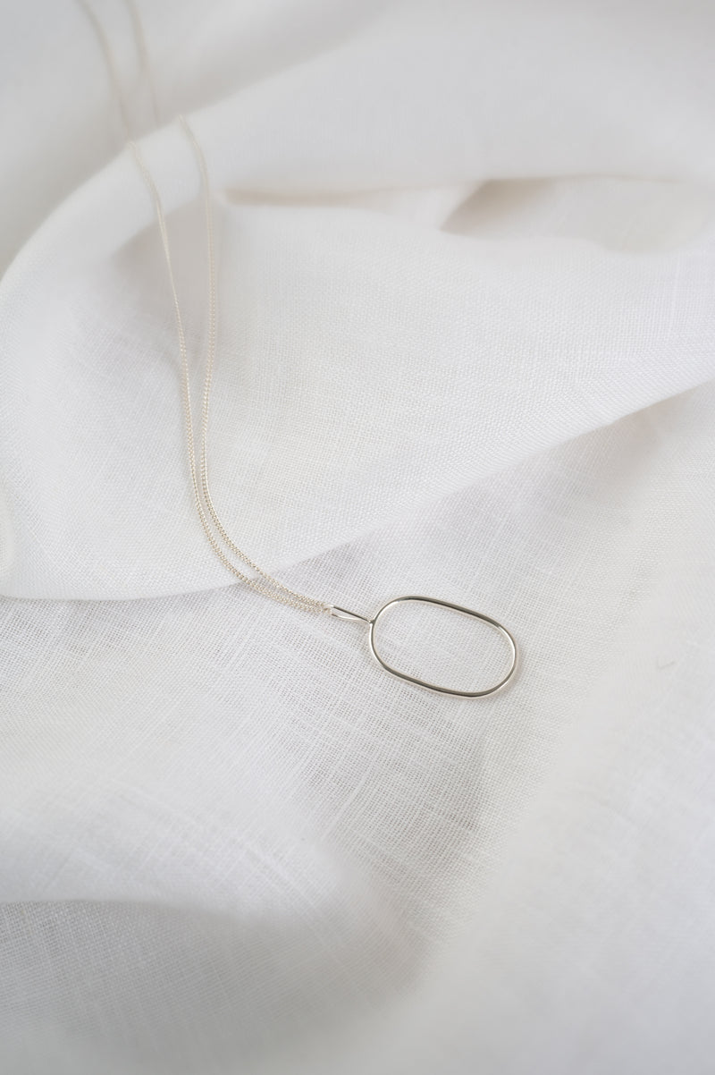 Silver necklace on a white fabric background