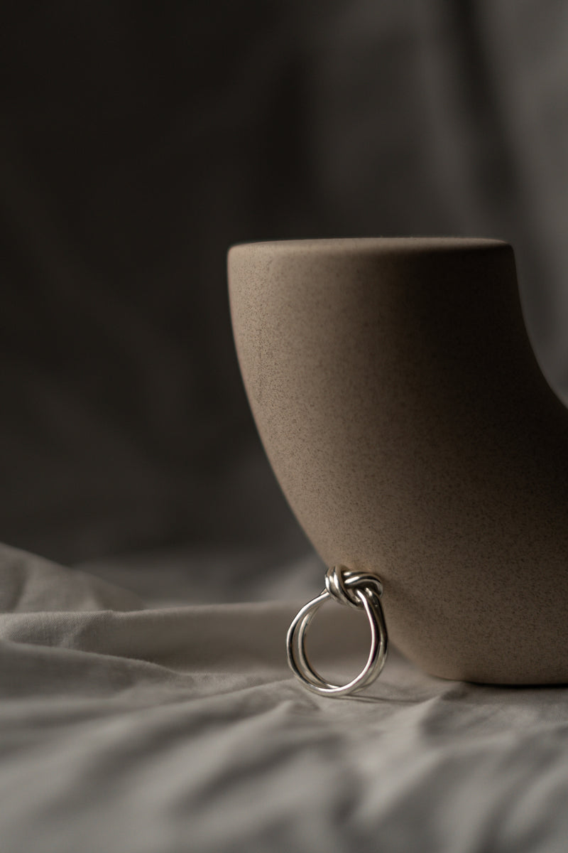 Brown ceramic cup with a silver ring on a textured surface