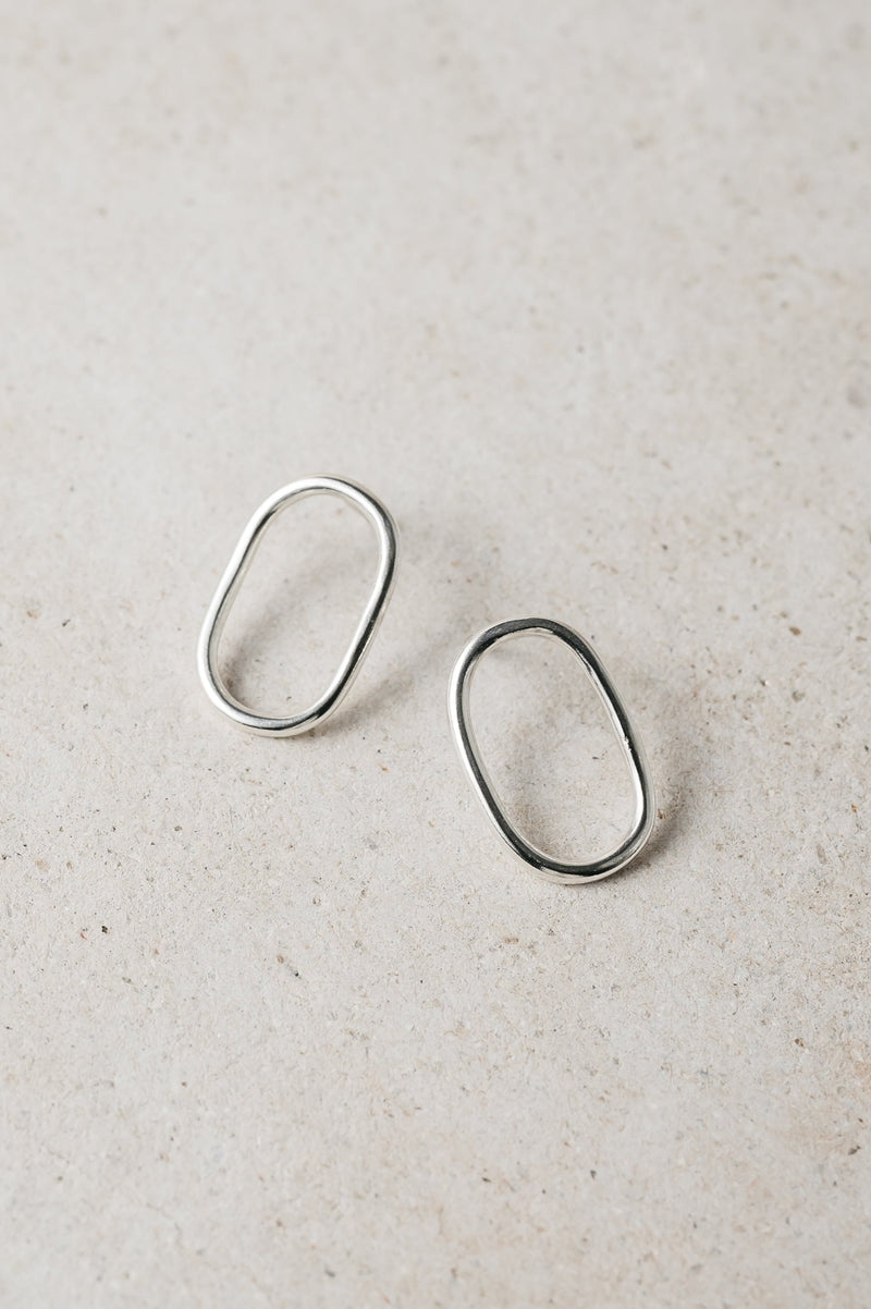 handmade silver oval studs on a grey background