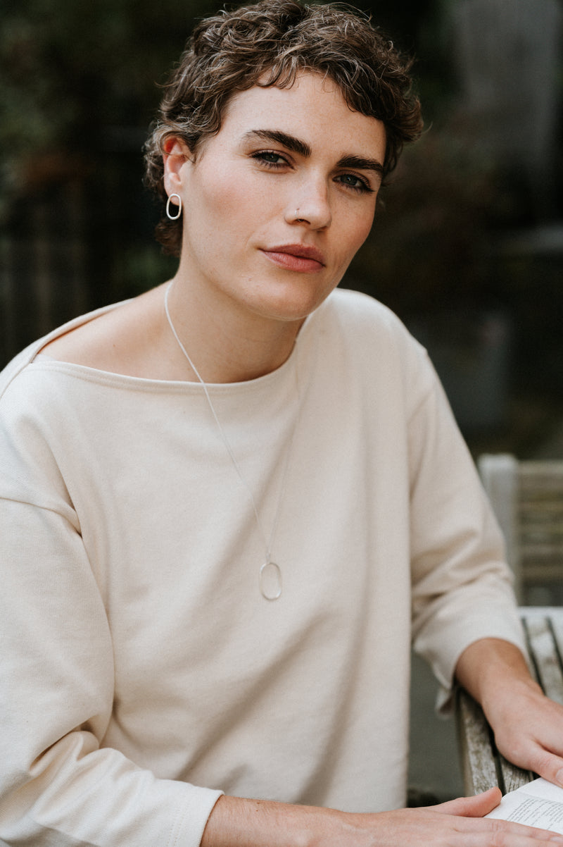 Person wearing a beige sweater sitting outdoors