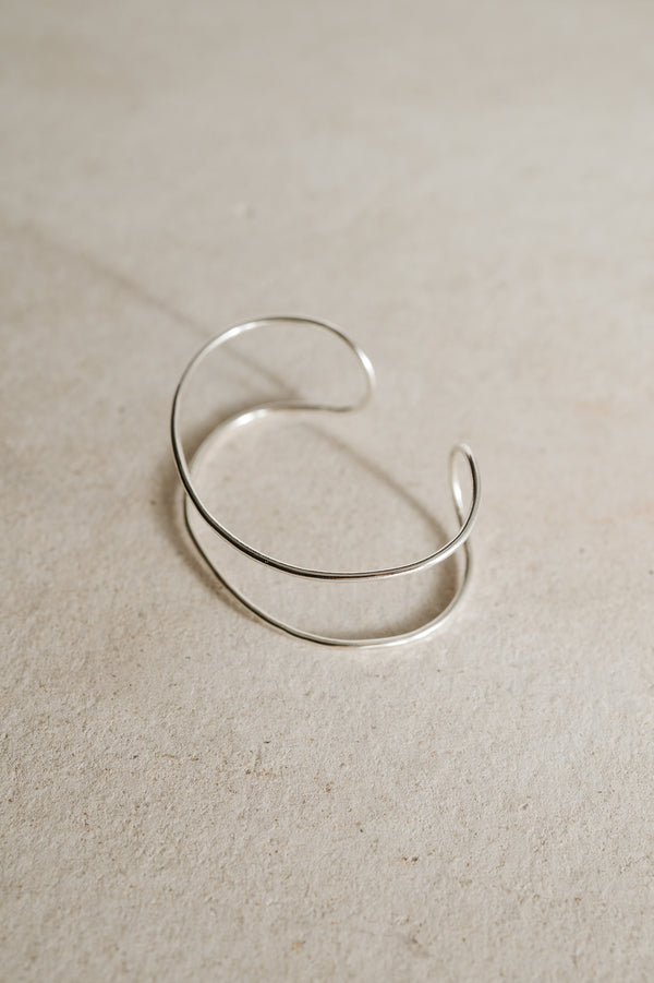 Double band silver cuff bracelet handmade from recycled Sterling Silver with open gap on a beige background