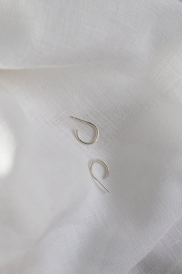 Pair of silver hoop earrings on a white fabric background