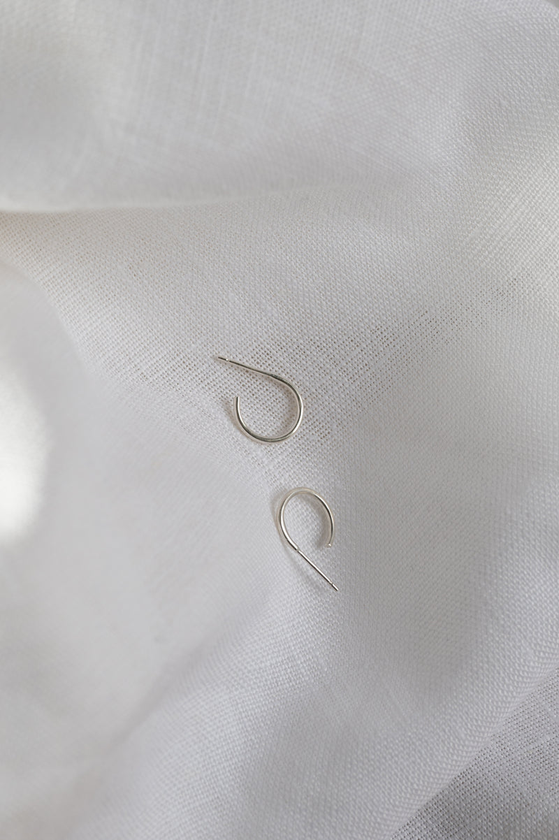 Pair of silver hoop earrings on a white fabric background