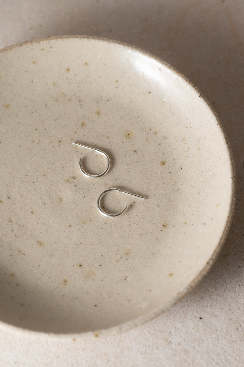 Close-up of a ceramic dish with silver hoopson a beige background