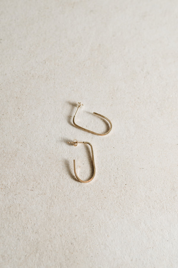 Minimalist open hoop earrings handmade from recycled Sterling Silver on a beige background