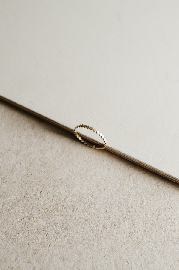 gold beaded stacking ring on a beige background