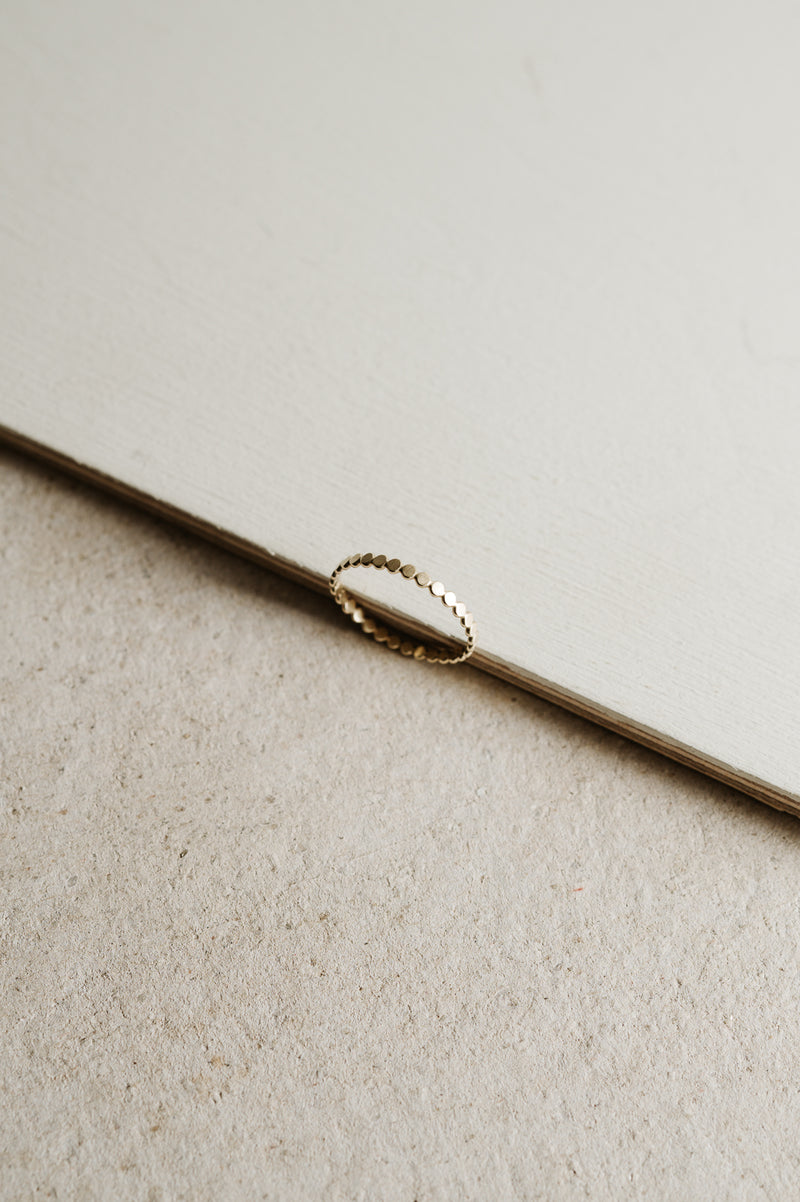 gold beaded stacking ring on a beige background
