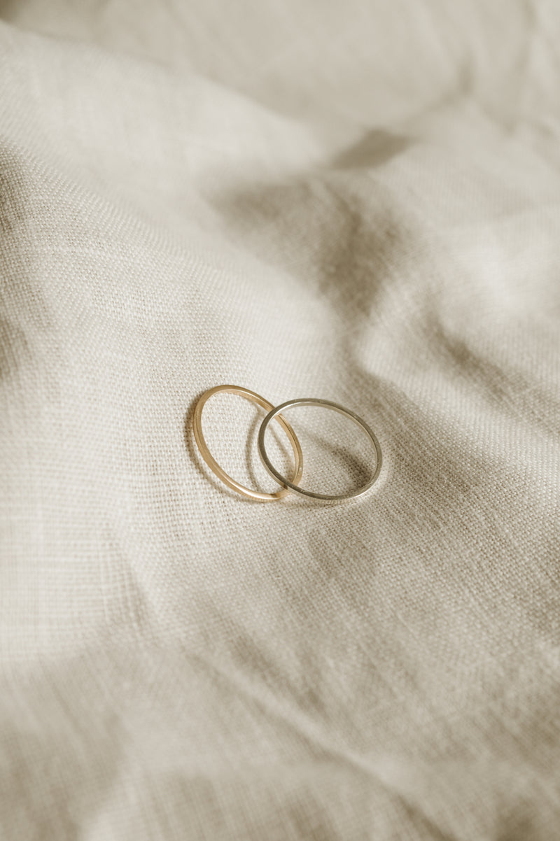 two handmade silver and gold stacking rings on a white fabric background