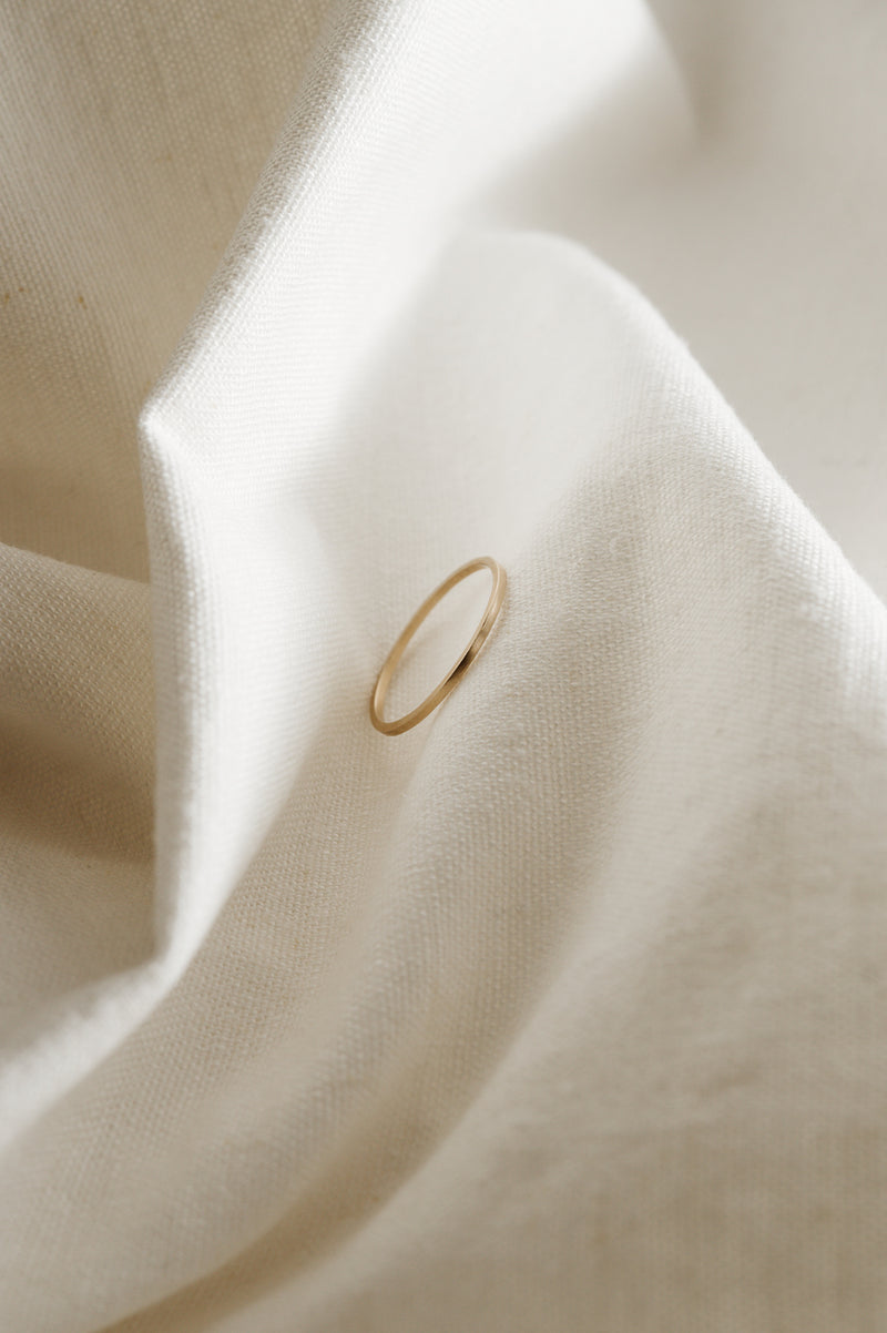 A single 9ct gold square wire stacking ring displayed on a white, textured surface.
