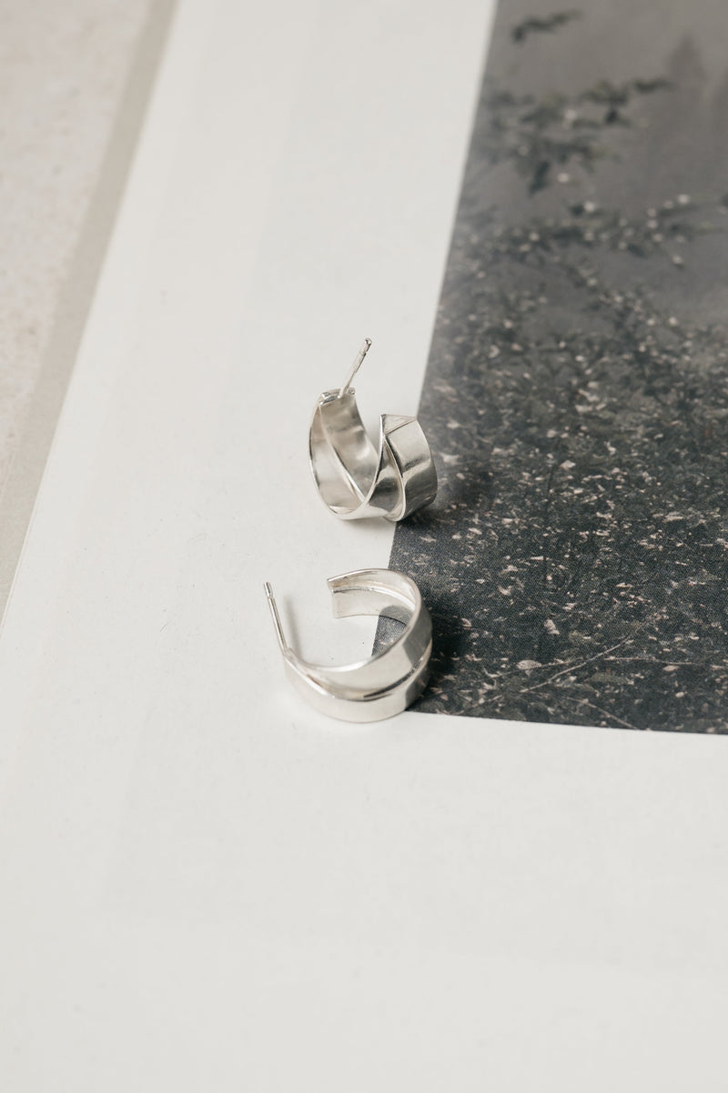 Silver hoop earrings on a reflective surface