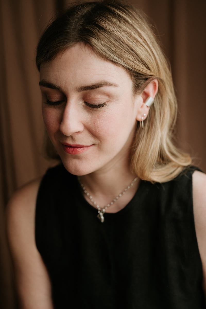 woman wearing studio adorn jewellery against a brown background