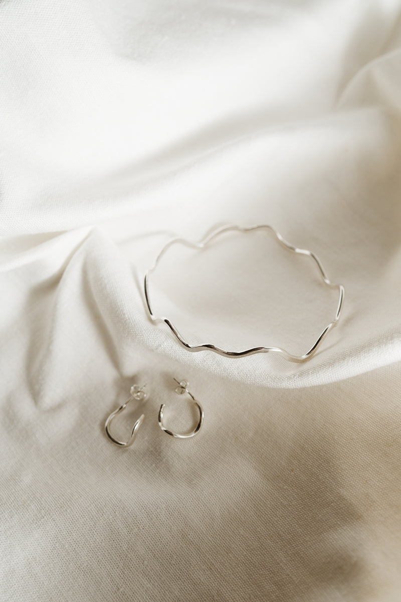 Recycled Sterling Silver Wiggle Bangle and wiggle hoops on white fabirc background