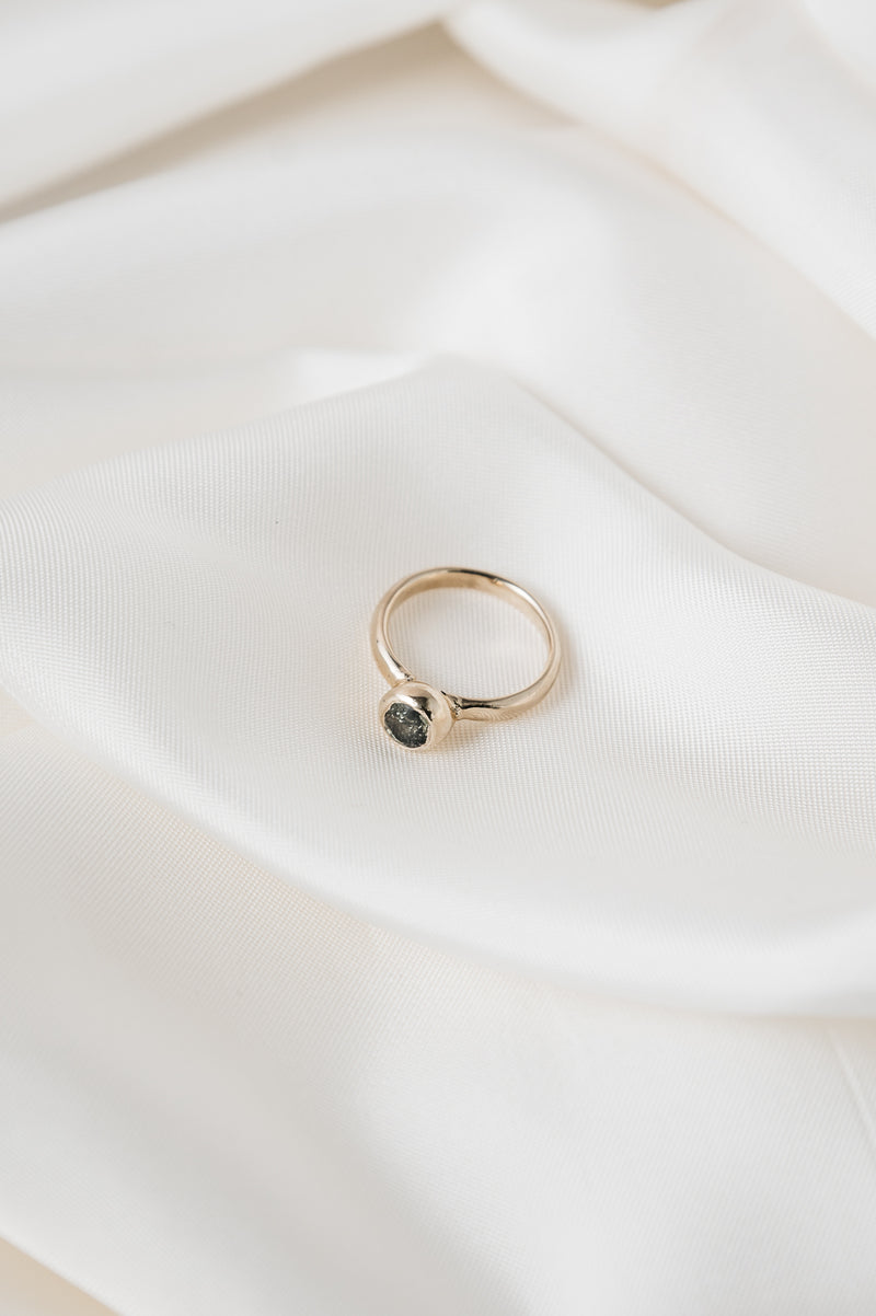 Gold ring with a black gemstone on a white fabric background