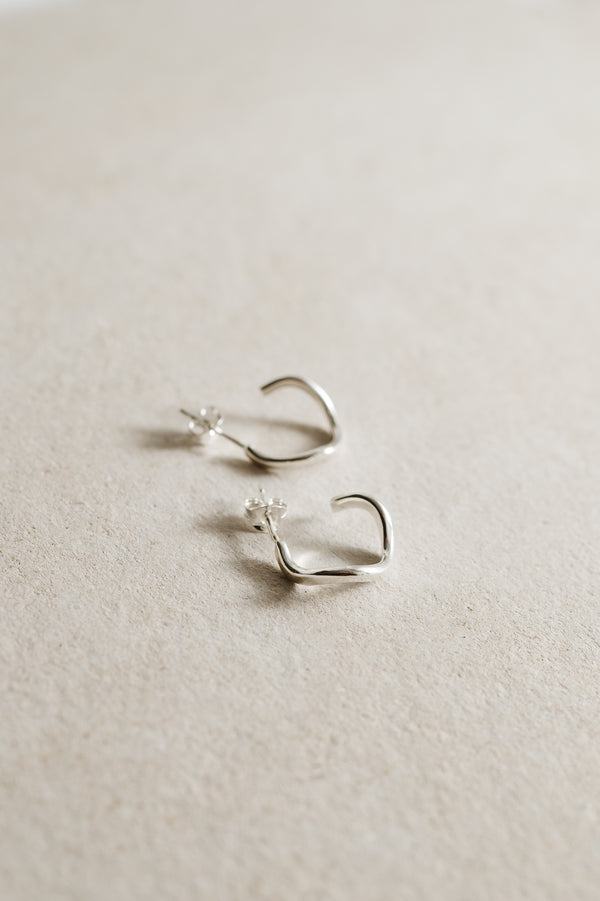 silver hoops earrings on a concrete background
