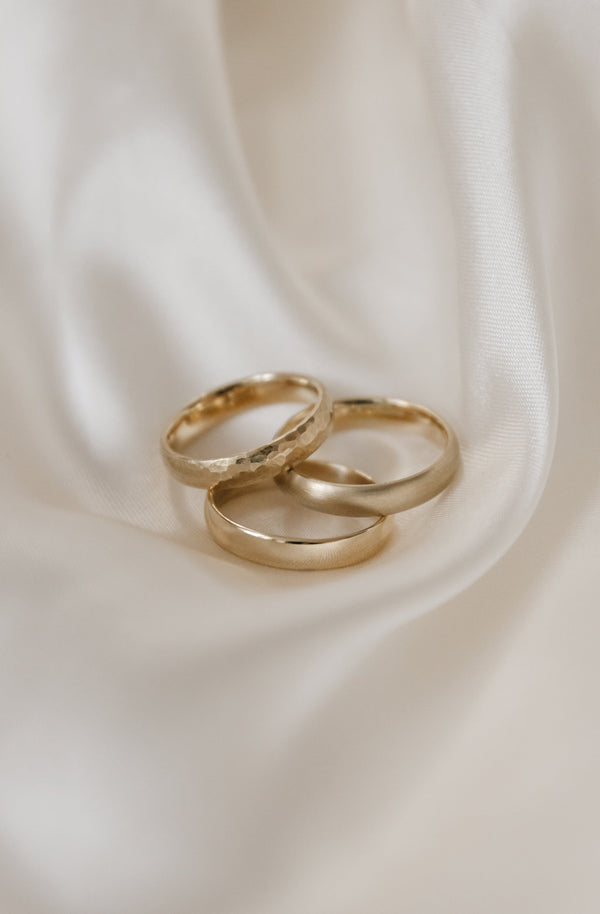 trio of handmade wedding bands on a white background