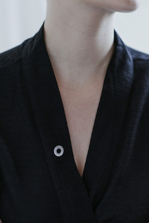 Model wearing handmade hammered mini round pin silver brooch by Studio Adorn