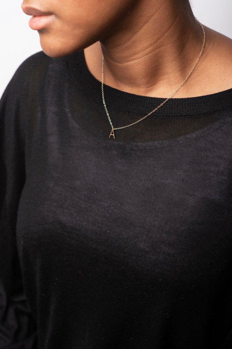 Studio Adorn front profile of model wearing mini 9ct gold initial pendant necklace on a fine curb trace chain 