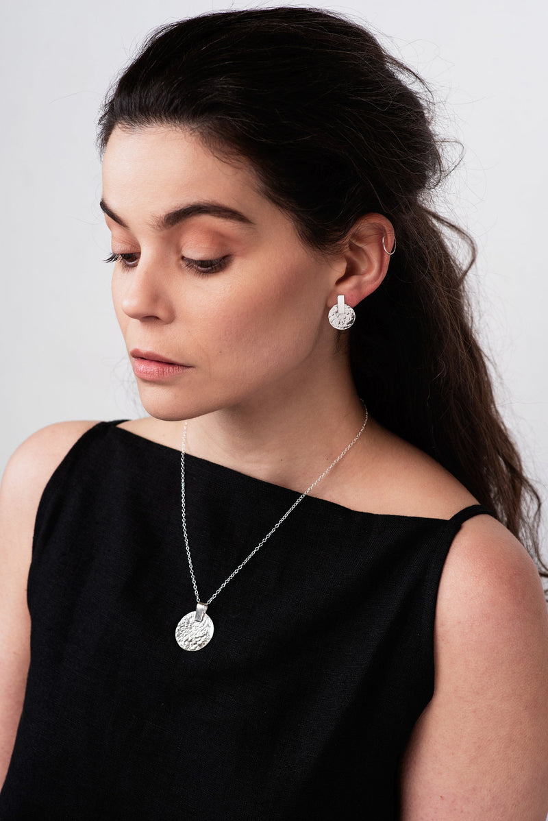 Model wearing silver hammered disc stud earrings handmade by Studio Adorn