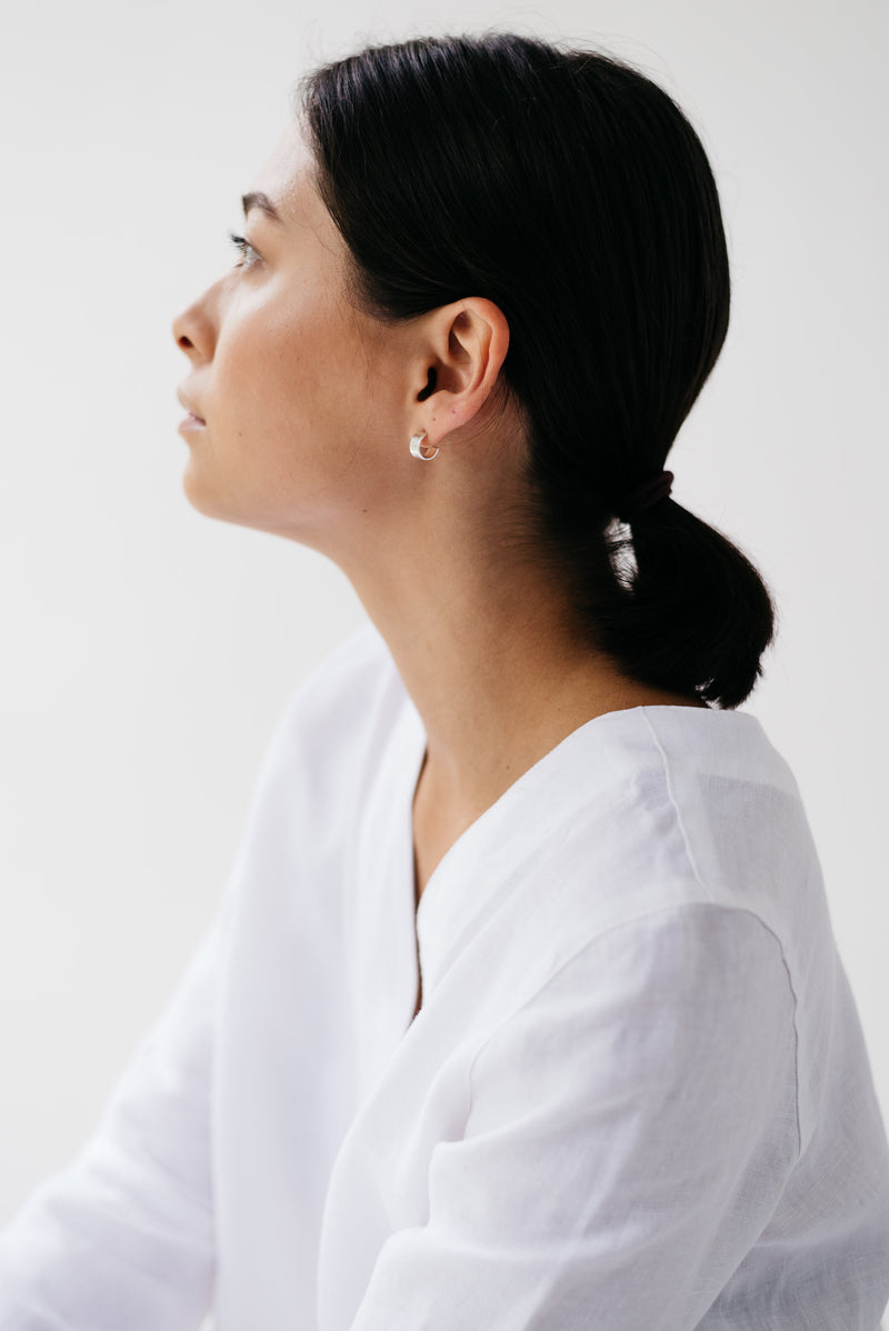 Model wearing mini hammered huggy hoop silver earrings handmade by Studio Adorn