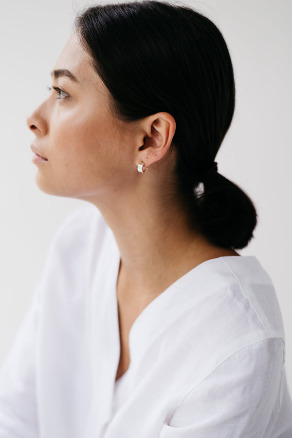 Model wearing mini hammered huggy hoop silver earrings handmade by Studio Adorn