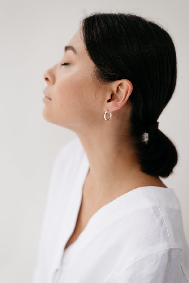 Model wearing simple silver minimal hoop earrings handmade by Studio Adorn