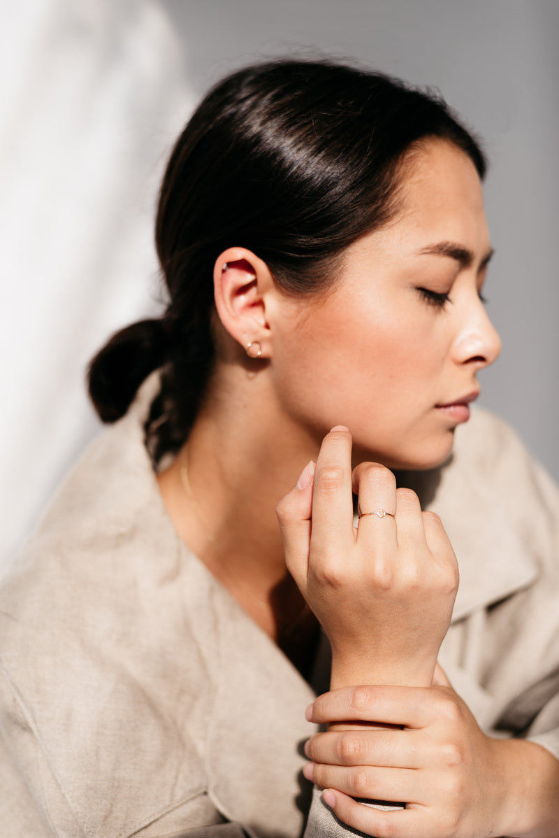 Studio Adorn side profile of model wearing mini gold circle ring on  middle index finger and 9ct gold mini circle stud earrings 