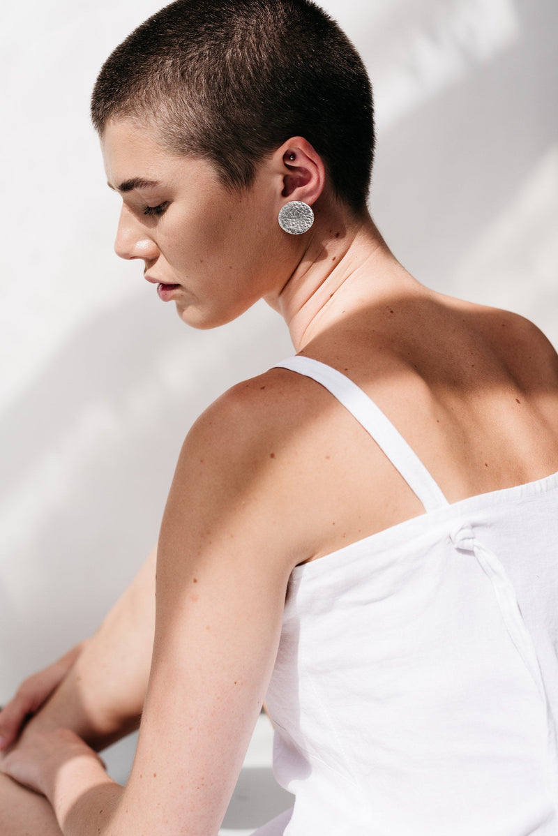 Model wearing silver hammered disc statement stud earrings handmade by Studio Adorn