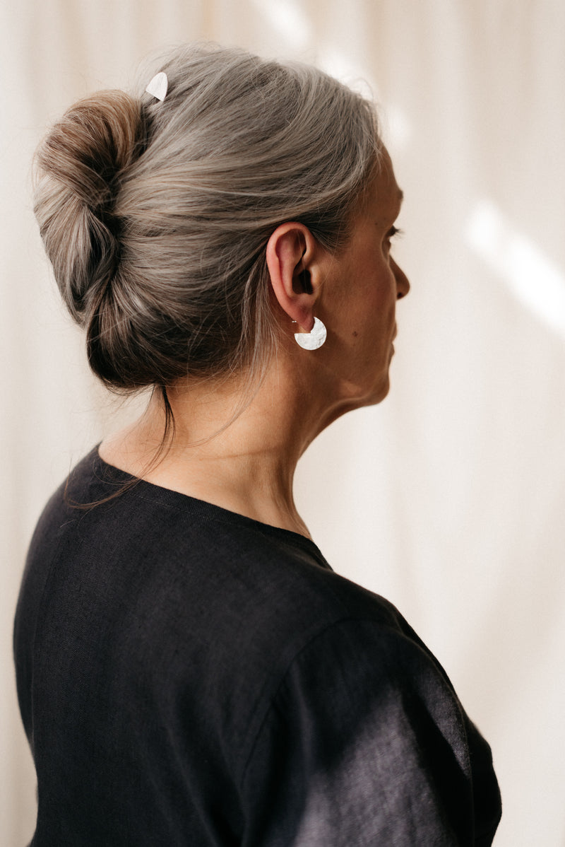 Model wearing circle cut out silver hammered disc earrings handmade by Studio Adorn