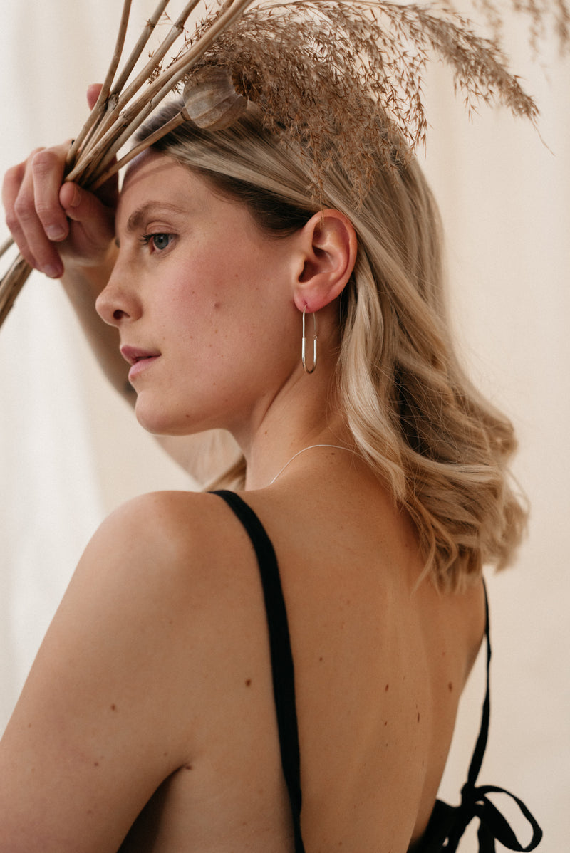Model wearing chunky Oval silver statement hoop earrings handmade by Studio Adorn