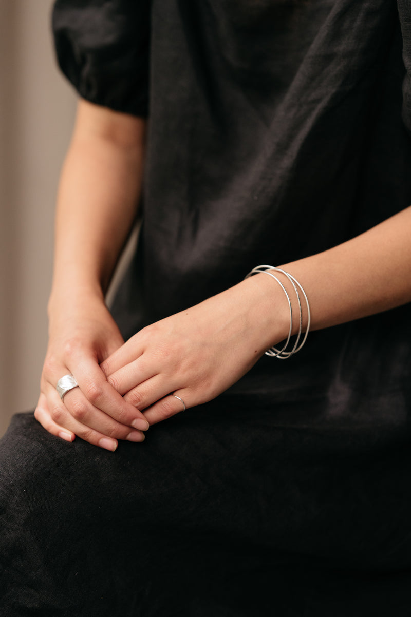 Organic Shaped Bangles stacked together on a womans wrist made by Studio Adorn Jewellery from Recycled Silver
