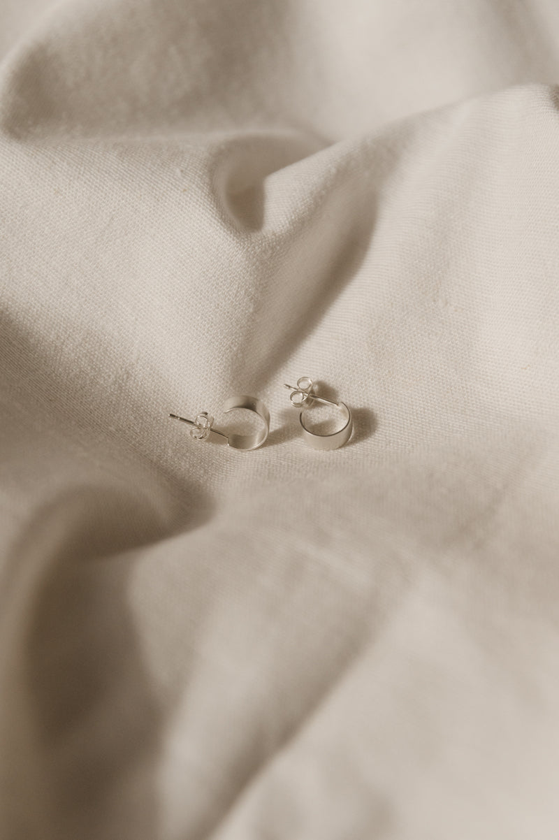 silver huggy hoops on white fabric backgroud
