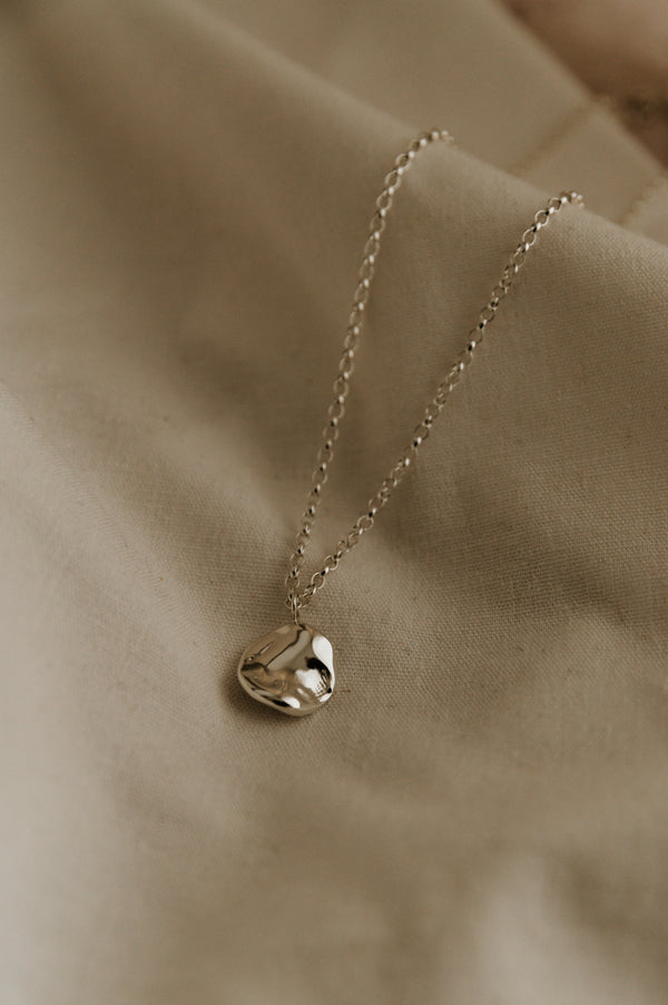 Studio Adorn - Molten Disc Fluid Silver Necklace on a neutral background