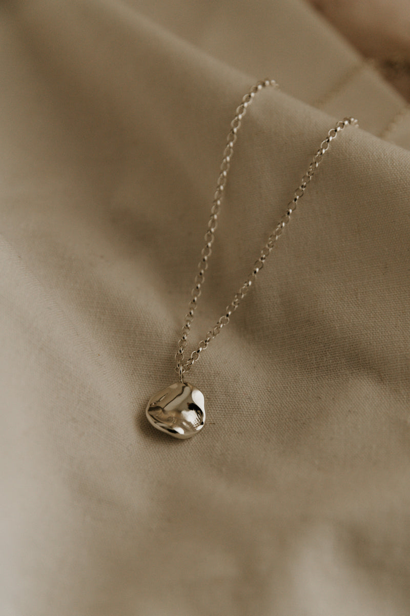Studio Adorn - Molten Disc Fluid Silver Necklace on a neutral background