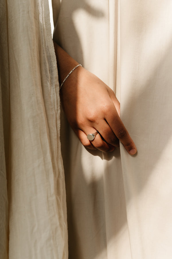 womans hand wearing a round signet ring in sterling silver