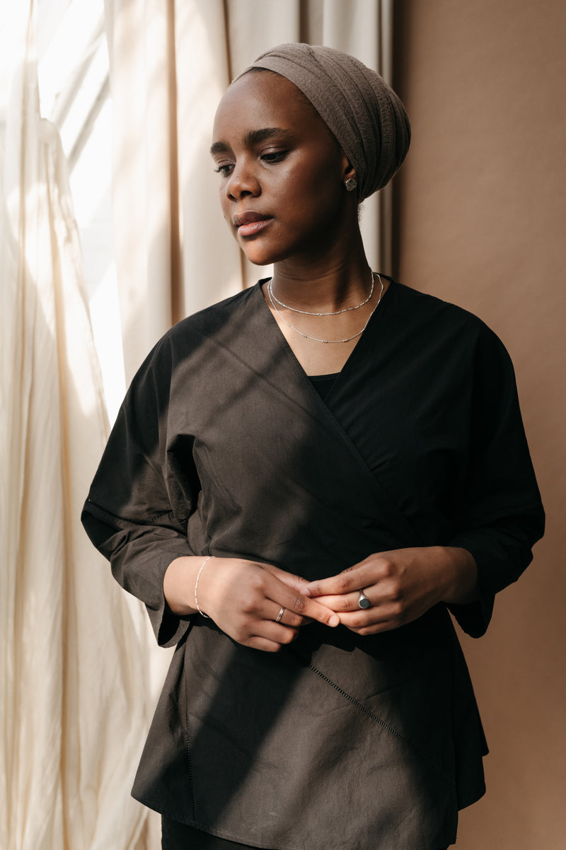 woman standing against a neutral background wearing silver jewellery