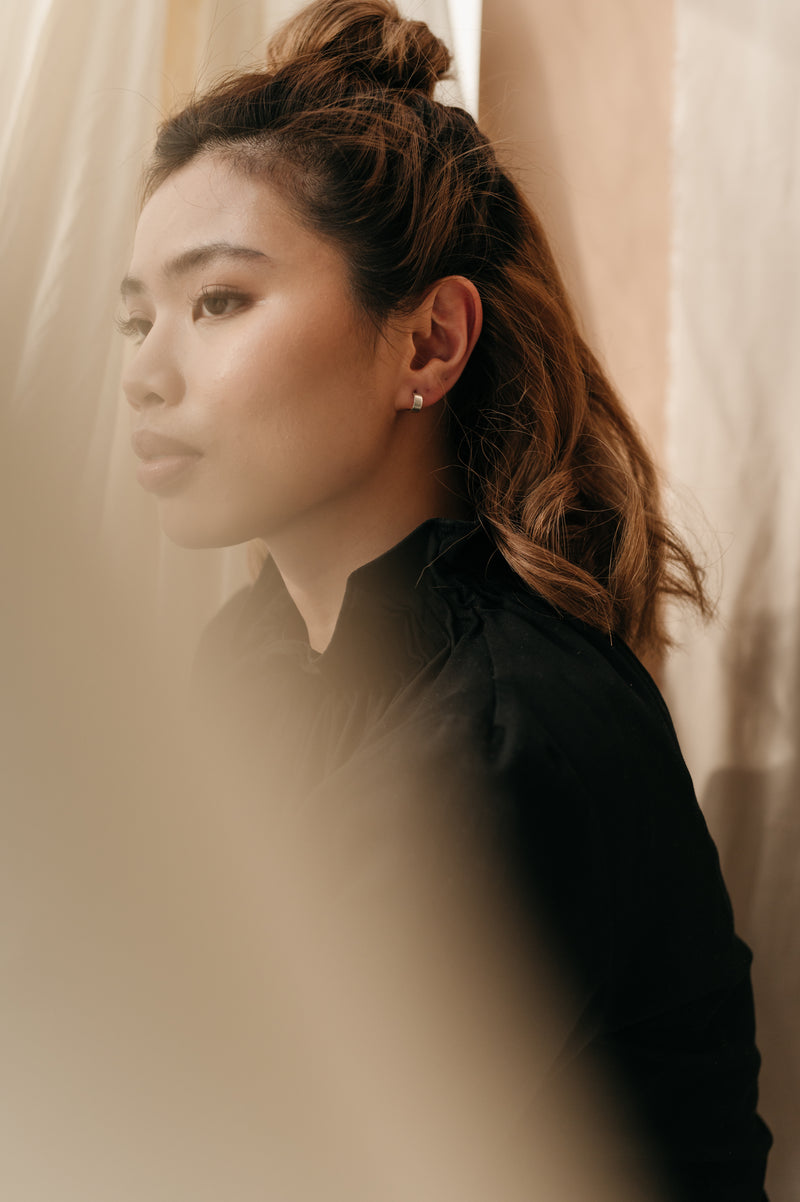 woman wearing a pair of silver huggy hoop earrings