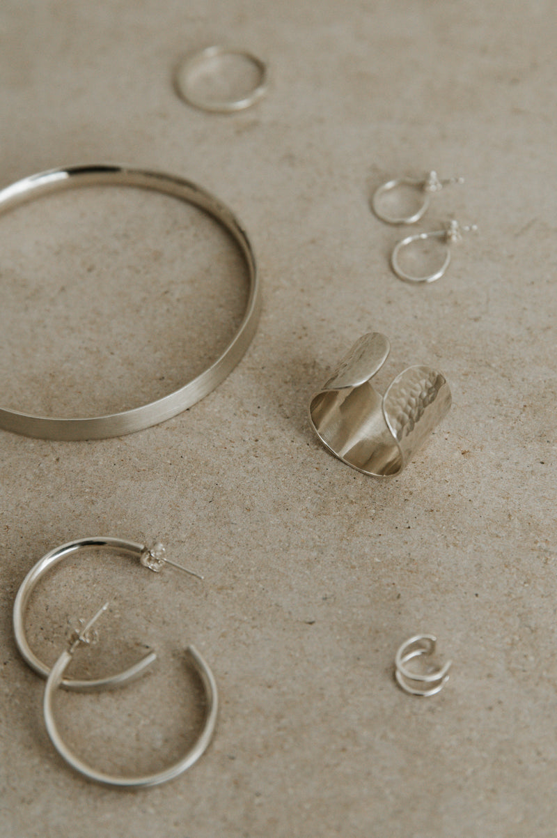 a selection of handmade silver jewellery n a neutral background