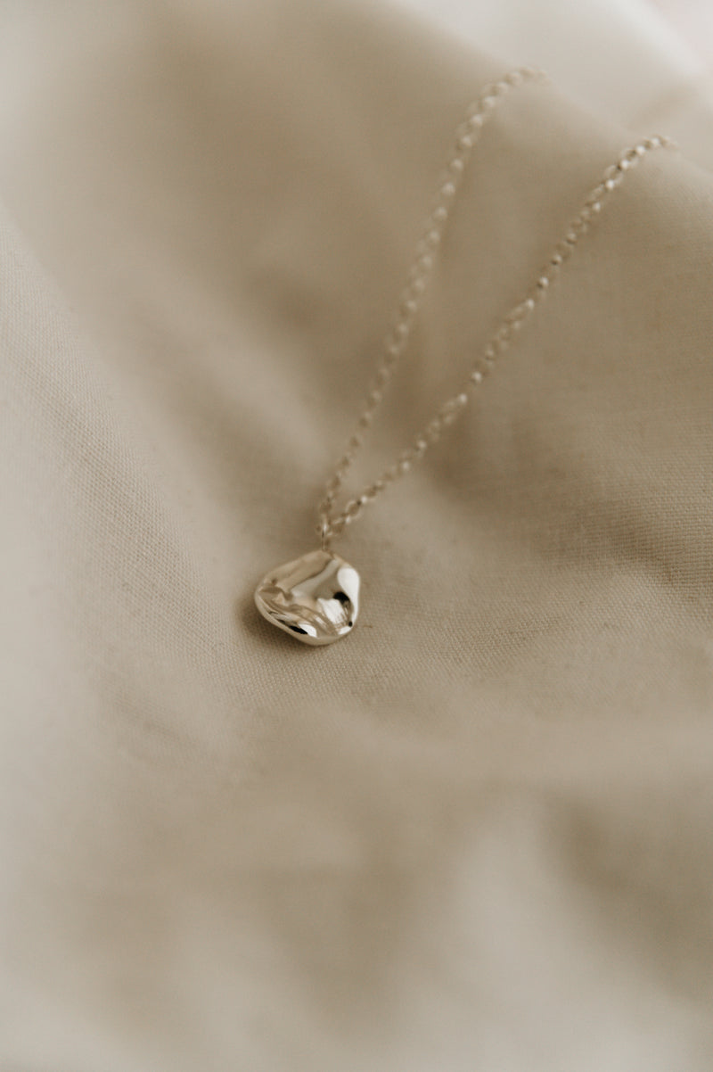 silver round sic necklace on a neutral background