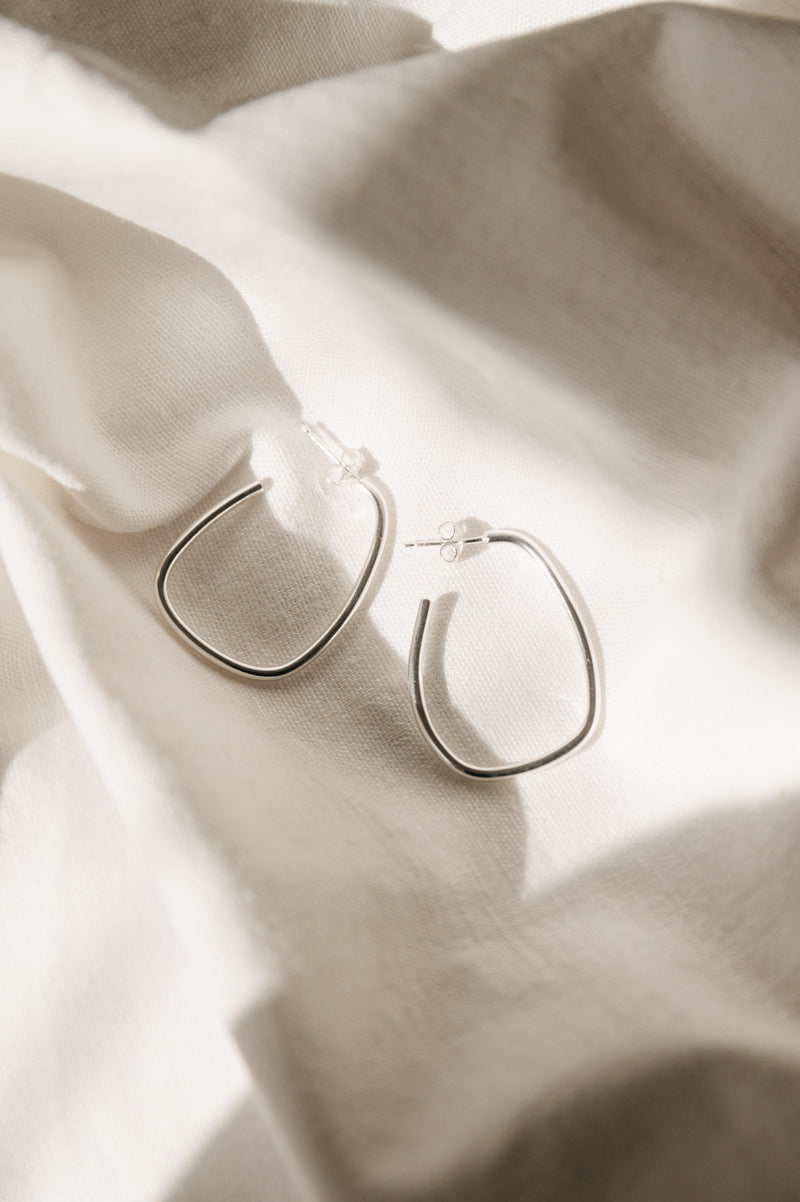 silver hoop earrings on white fabric background